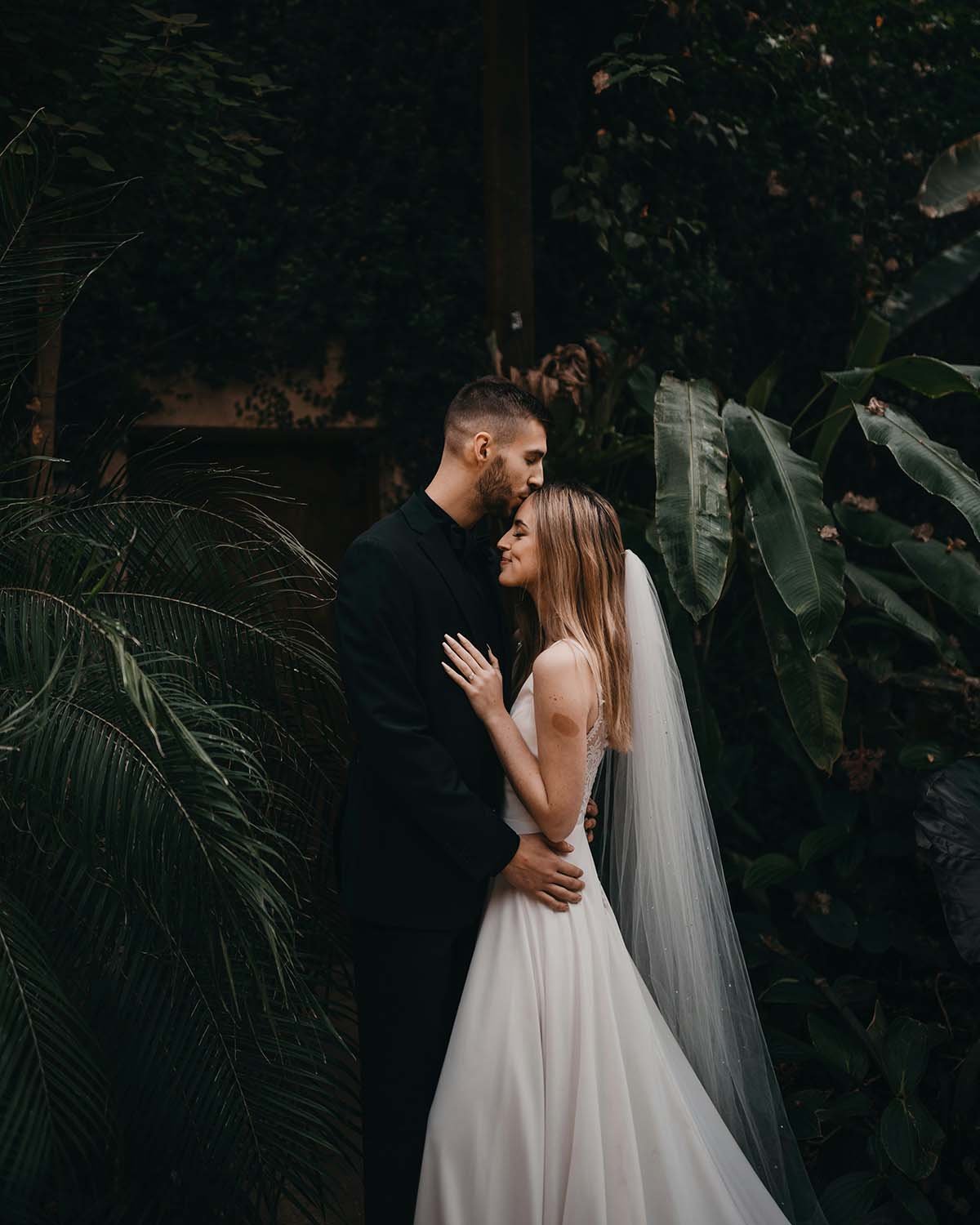 Bride and groom embracing among tropical foliage